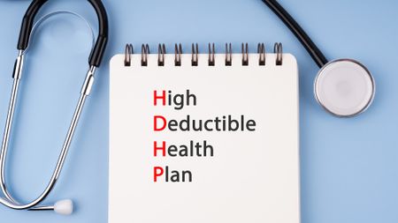 Stethoscope and notepad reading "high deductive health plan"