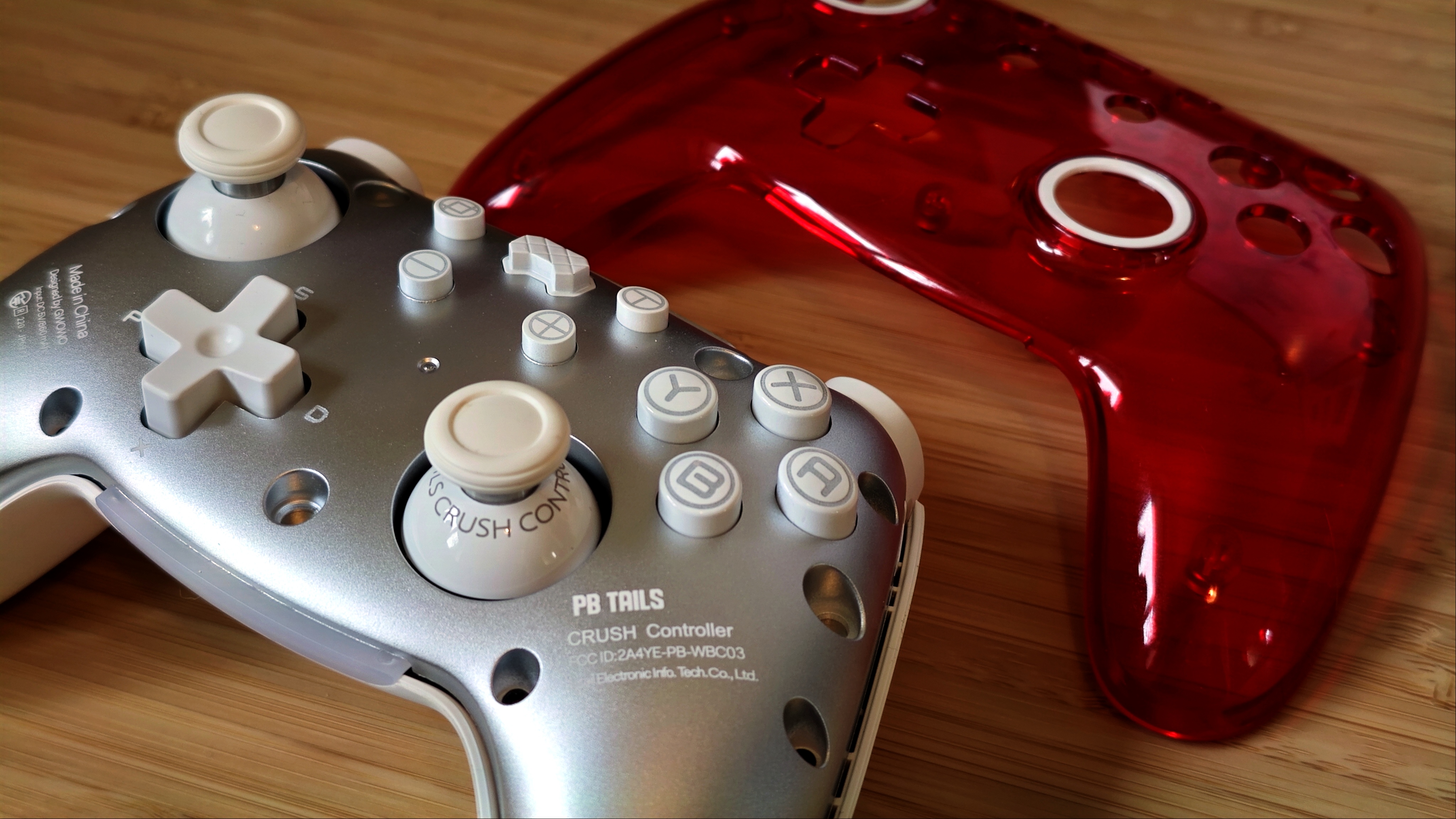 A Ruby red PB Tails gaming controller sitting on a wooden desk