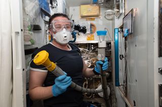 NASA astronaut Serena Auñón-Chancellor tackles plumbing duties inside the International Space Station's restroom, also known as the Waste and Hygiene Compartment.