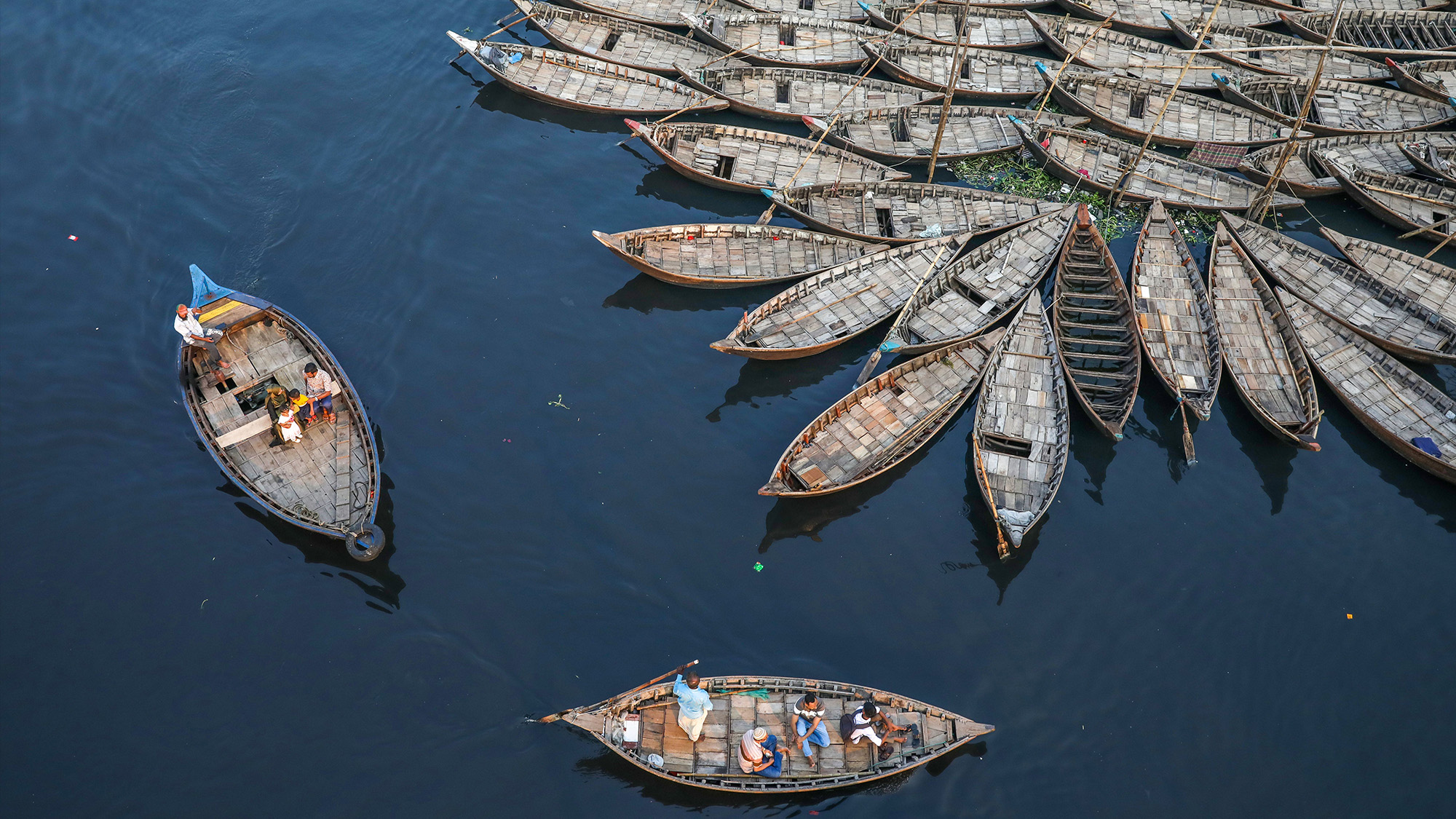 Boatmen ride their boats while other boats are anchored in the Buriganga river during the Eid al-Fitr holiday in Dhaka, Bangladesh