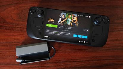 Steam Deck OLED next to Jsaux 5-in-1 Steam Deck dock on woodgrain desk.