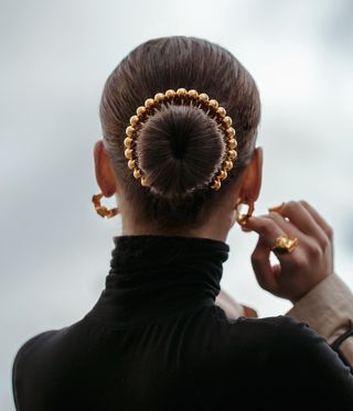 Back of woman's head, hair held back with a gold jewel