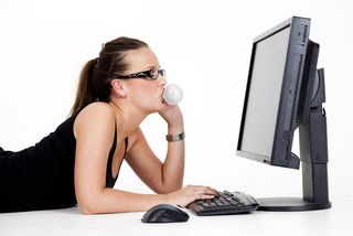 woman at computer blowing a bubble gum bubble