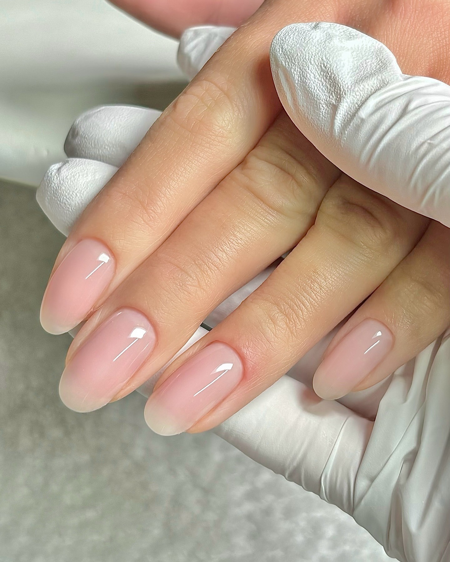 A woman with long, almond-shaped nails and a blurred French manicure design