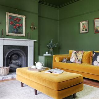 Green living room with mustard velvet sofa and footstool and Victorian-style fireplace