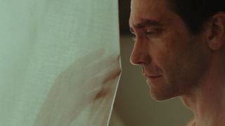 Jake Gyllenhaal looking at a hand through a curtain