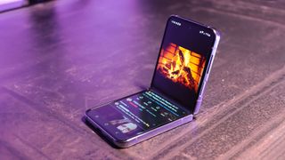 A shot of the Samsung Galaxy Z Flip4 phone partly folded with a video of a fireplace on the screen on a dark background