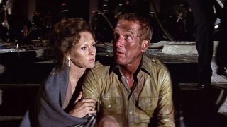 A woman sits next to and hugs a man in a still from the movie "The Towering Inferno"