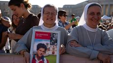 Nuns hold up photos of St. Carlo Acutis and St. Pier Giorgio Frassati at their canonization