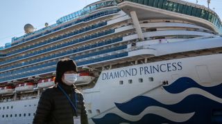 A member of the media wears a face mask while walking past the Diamond Princess cruise ship at Daikoku Pier in Yokohama, Japan, on Feb. 10, 2020.