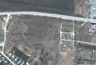 This photo, taken on March 19, 2022, by Maxar Technologies' WorldView-3 satellite, shows the early excavation of the mass grave in Manhush, Ukraine, which is next to a previously existing cemetery (center right).