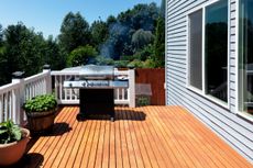 A gas grill on decking next to planters