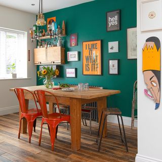 dining area with green and white wall frames on green wall dining table and chairs wooden flooring