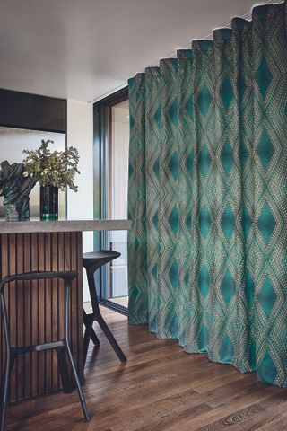 Green patterned curtains in room with bar and stools