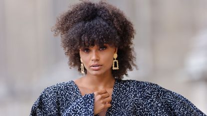 black model wearing statement gold earrings, gold jewellery