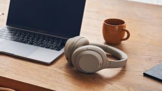 Beige Sony wireless headphones next to a laptop and mug