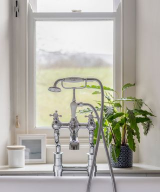 bathroom shower tap mixer over a bath with country view through window
