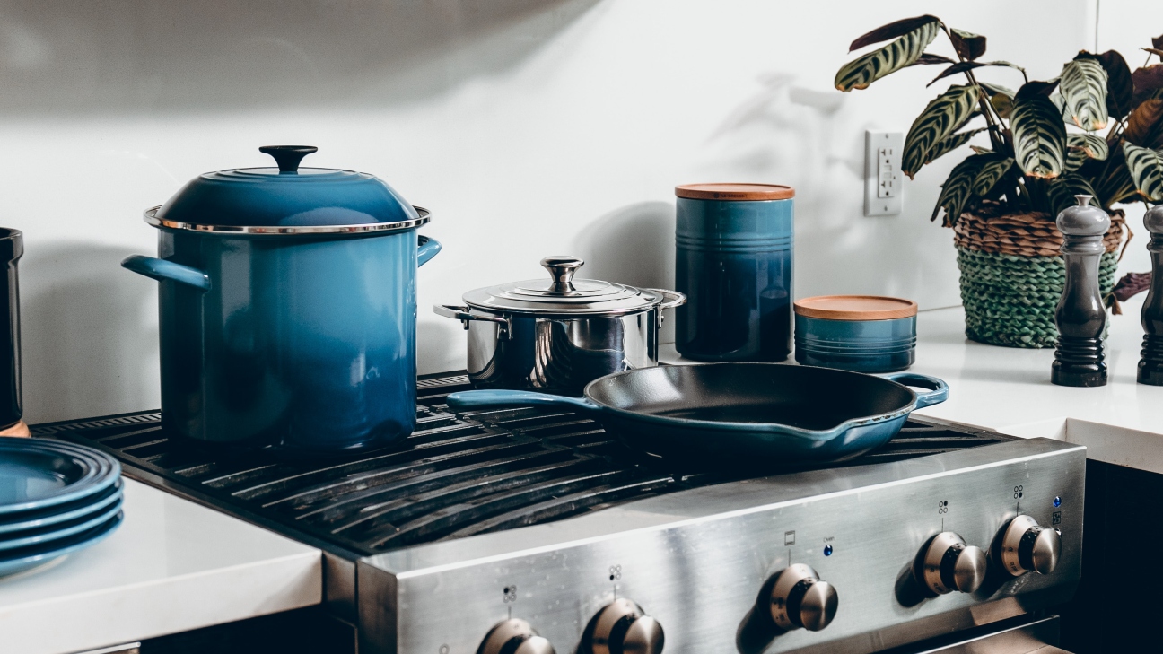 Kitchen bench with oven and blue pan and pots, salt and pepper shakers and a plant