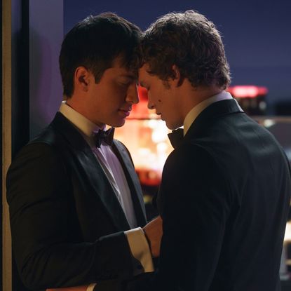 Two men (Hudson Williams as Shane Hollander and Connor Storrie as Ilya Rozanov) stand closely in front of a city skyline at night, in the TV show 'Heated Rivalry.'
