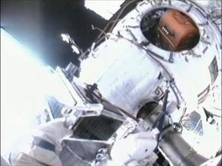 Russian cosmonaut Sergei Volkov holds onto ARISSat-1, an amateur ham radio satellite, during a spacewalk on Aug. 3, 2011. The amateur satellite was manually released into orbit off the back end of the station's Russian segment.