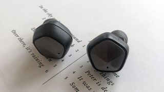 Astell & Kern UW1000 earbuds on surface showing song lyrics