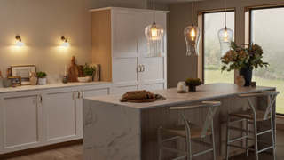 Kitchen with pendant lights above a marble island and wall sconces above a white worktop in the background