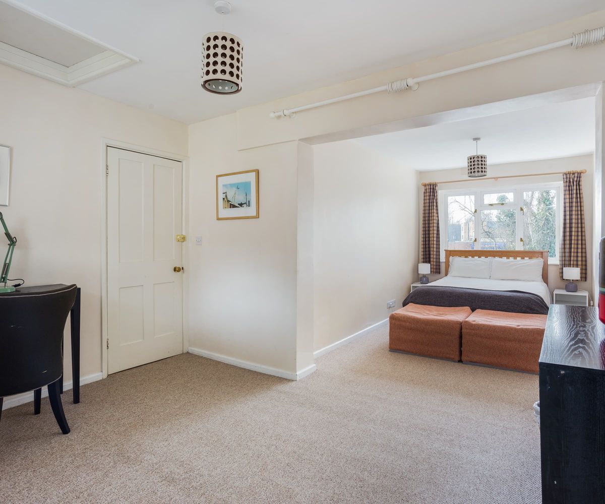 A open-plan bedroom with white walls and grey carpet