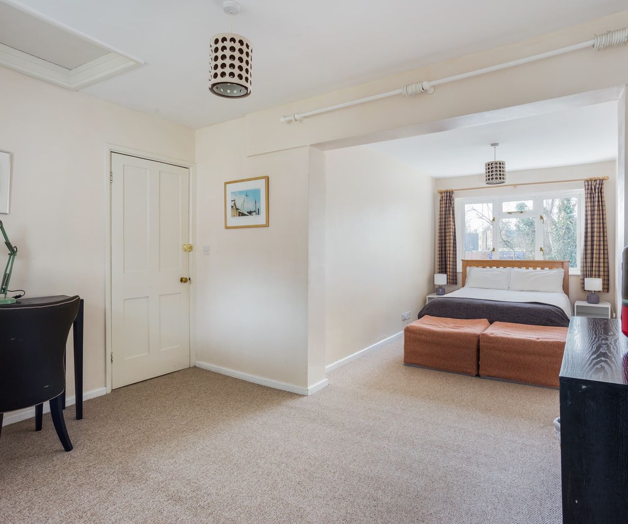 A open-plan bedroom with white walls and grey carpet