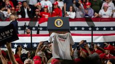 A woman holds a Trump 2024 t-shirt at a rally during the 2020 election.