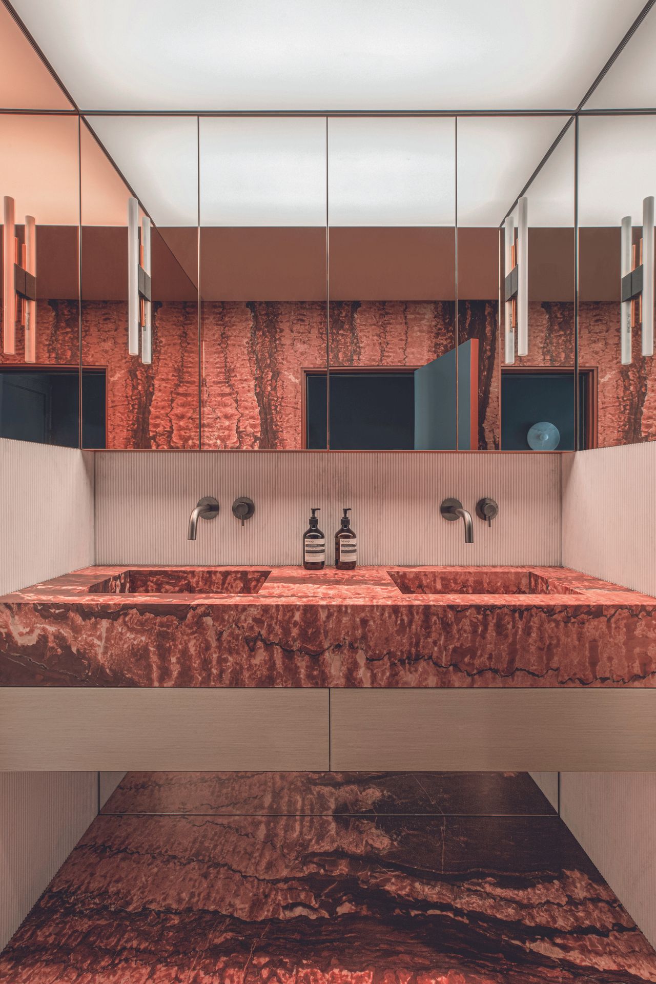 An Earthy toned textured stone bathroom with wrap around mirror cabinets