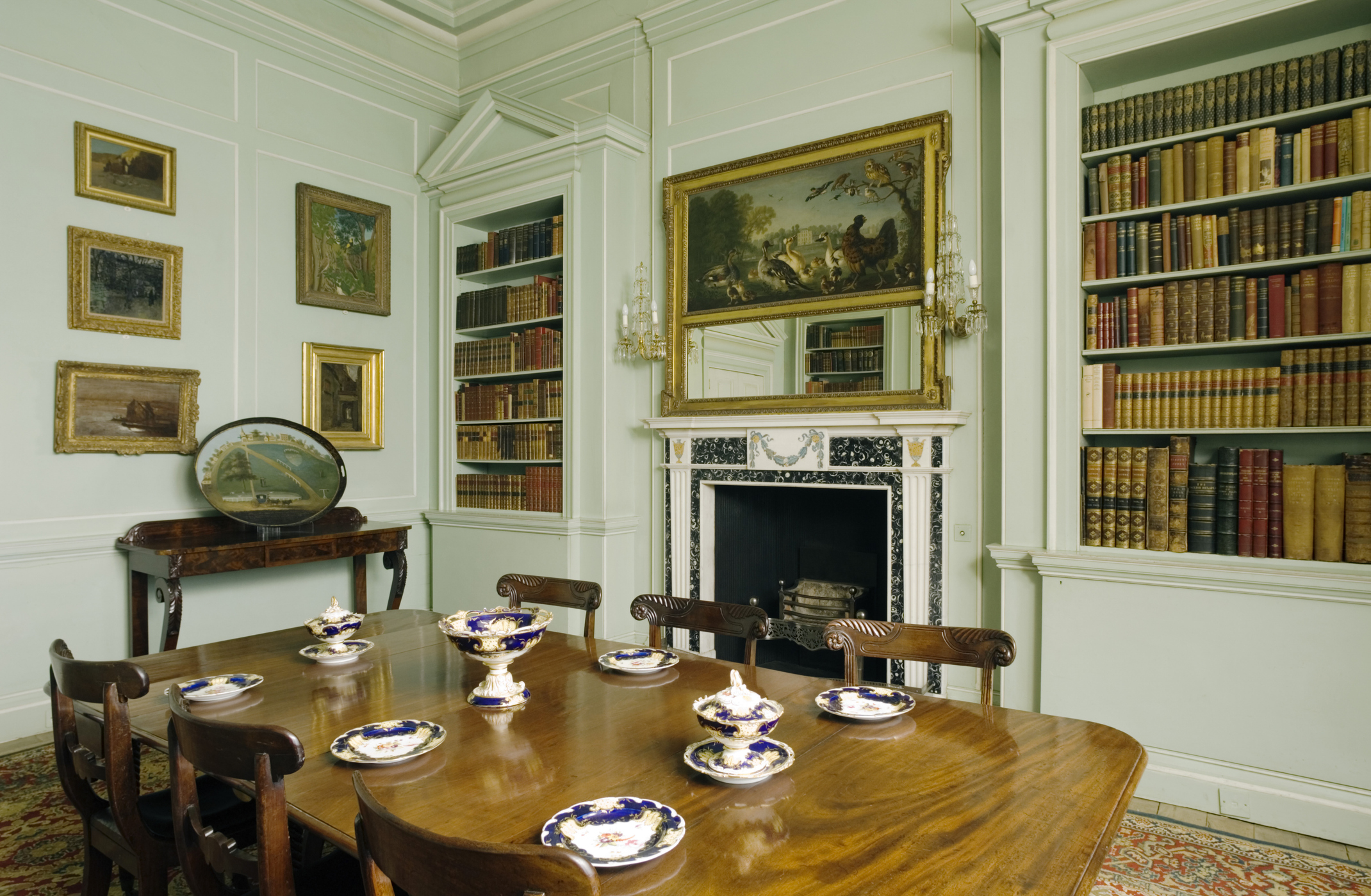 The Green Library with a William IV mahogany dining table and chairs at Mottisfont, Hampshire. The fireplace is by Bossi and is made of black and white Irish fossil marble