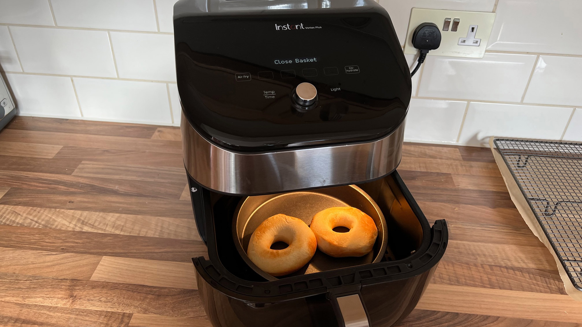 Two donuts in a metal can in the basket of the air fryer, under preparation