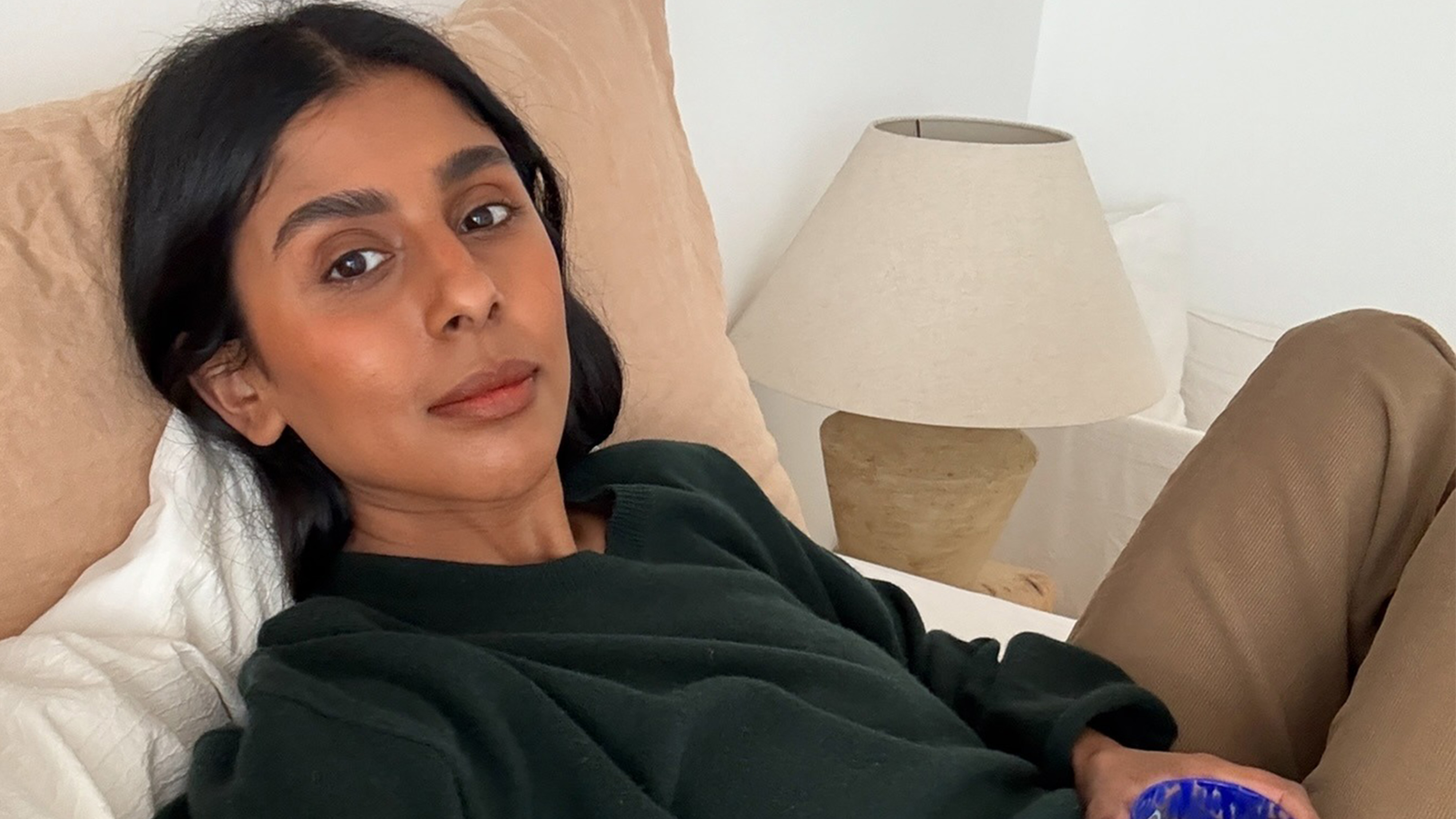 Monikh wears a green sweater and khaki-colored pants.