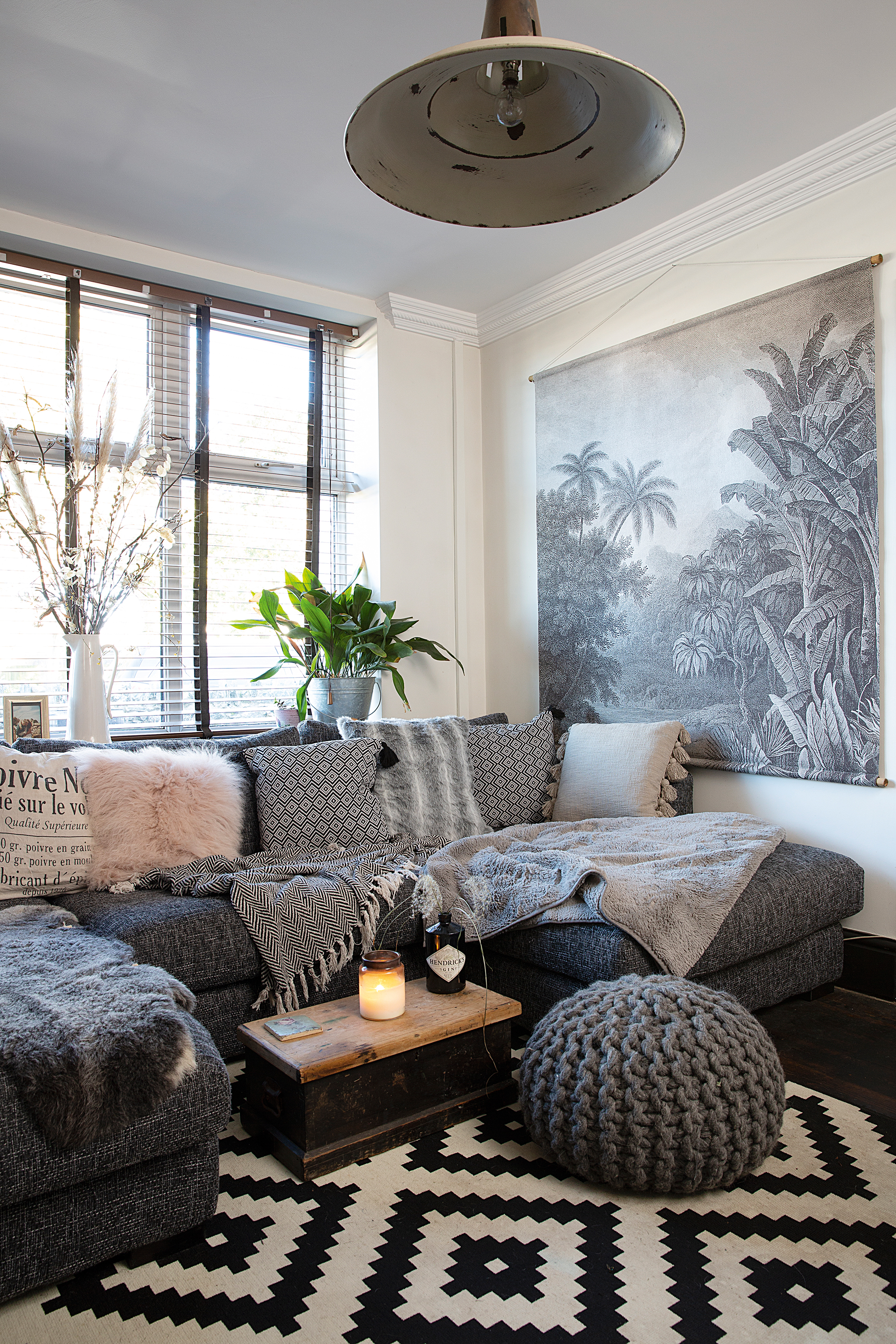 A grey living room with large corner sofa, coffee table and monochrome rug