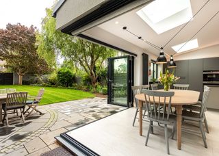 kitchen extension with bifold doors opening up entire corner. There is a dining table in the corner of the kitchen.