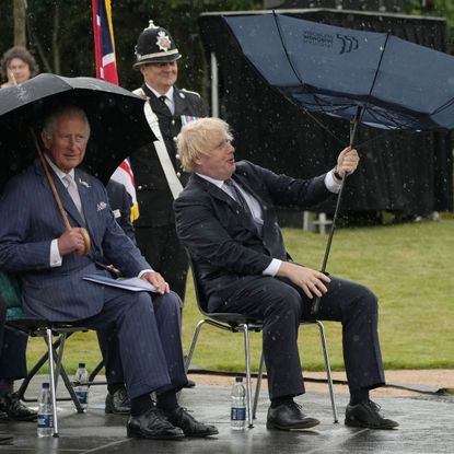 stafford, england july 28 prince charles, prince of wales looks on as c british prime minister, boris johnson r opens his umbrella at the national memorial arboretum on july 28, 2021 in stafford, england the police memorial, designed by walter jack, commemorates the courage and sacrifice of members of the uk police service who have dedicated their lives to protecting the public the memorial is set on grounds landscaped by charlotte rathbone within the national memorial arboretum and stands along with 350 memorials for the armed forces, civilian organisations and voluntary bodies who have played their part serving the country photo by christopher furlong wpa poolgetty images