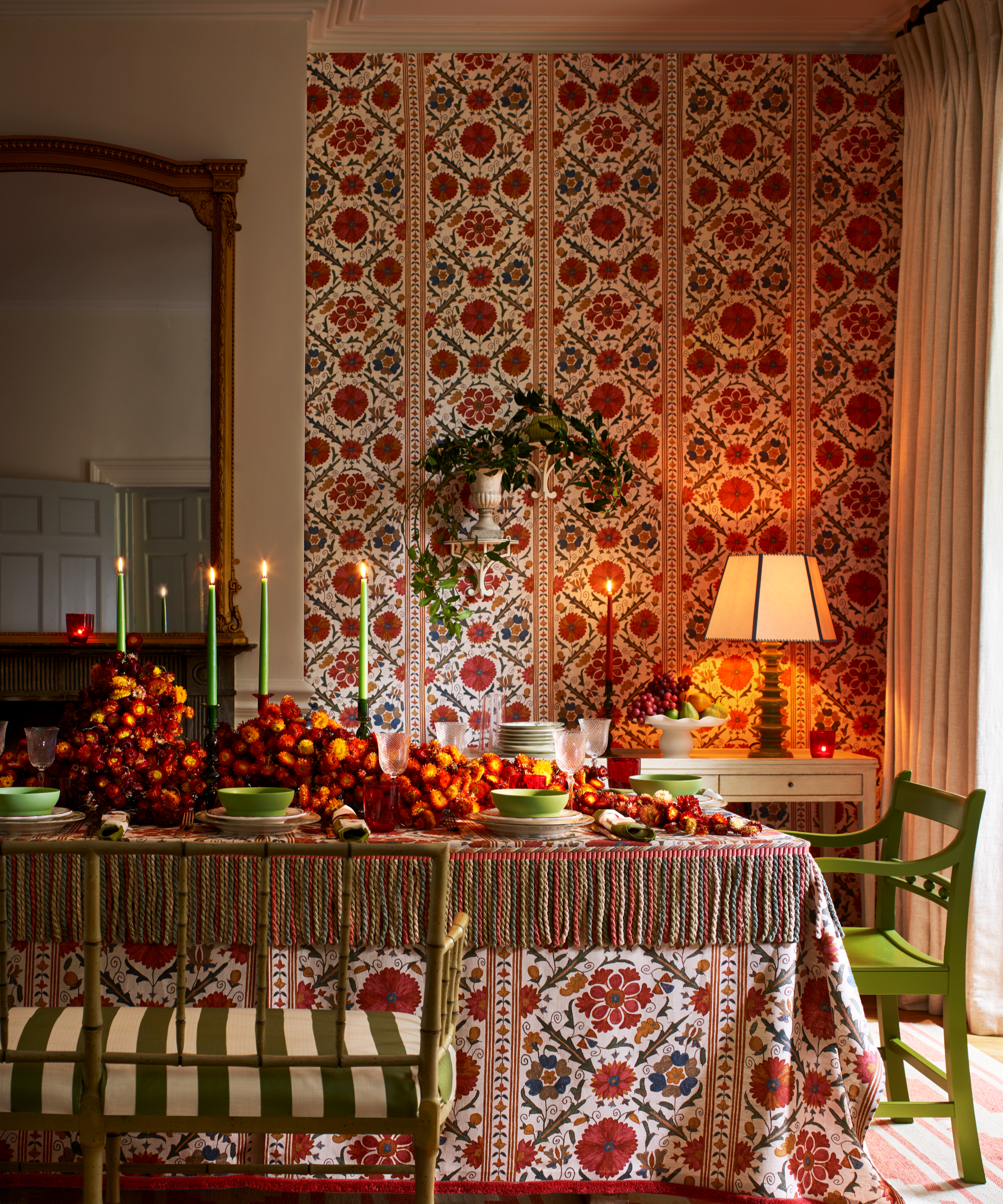 a festive Christmas dining room with wallpapered walls, a festive tablescape with candles, decorative fruits, a patterned table cloth, and a warm, inviting, cozy atmosphere