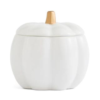 A cream ceramic candle shaped like a pumpkin