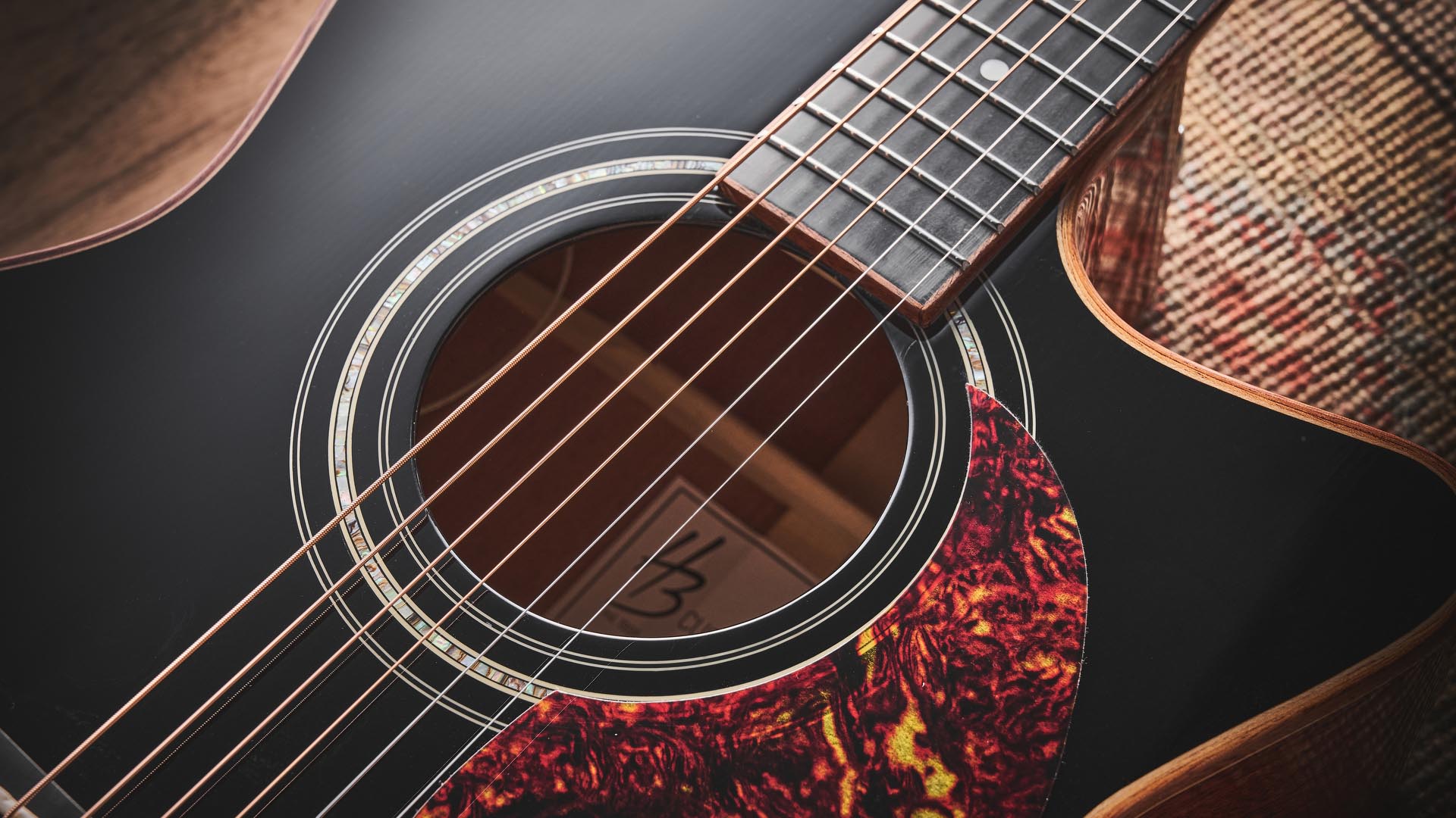 Harley Benton CLG-650SM-CE Black: the handsome but affordable cutaway acoustic isd photographed against a patterned rug on a wooden floor.
