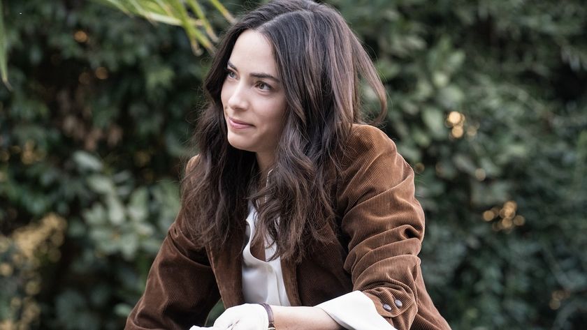 Lala Dominguez smirking as she&#039;s holding some evidence and kneeled down in NCIS: Origins