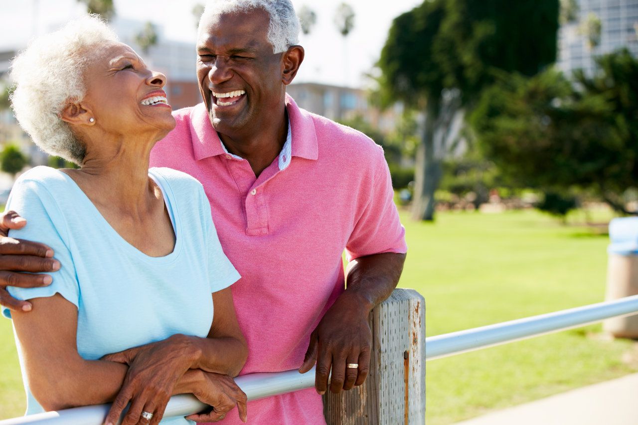 Senior Couple Walking In Park Together Laughing