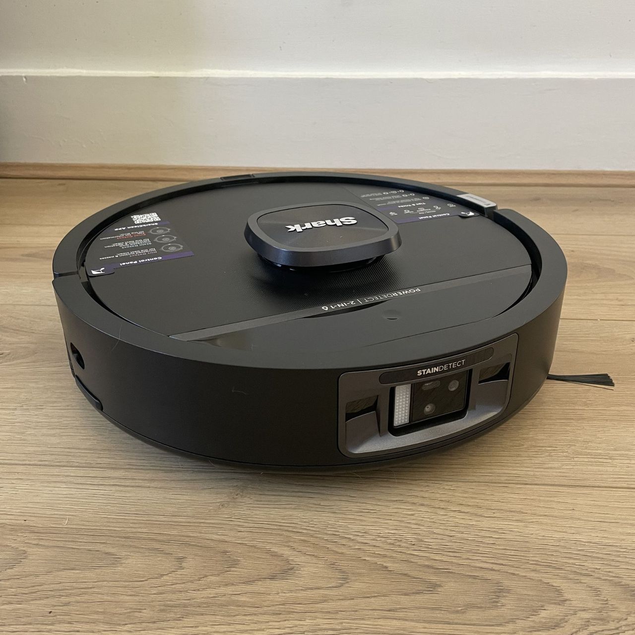 Bot of the Shark PowerDetect UV Reveal 2-in-1 Vac &amp; Mop Robot Vacuum RV3000XEUK sitting on wood-effect flooring
