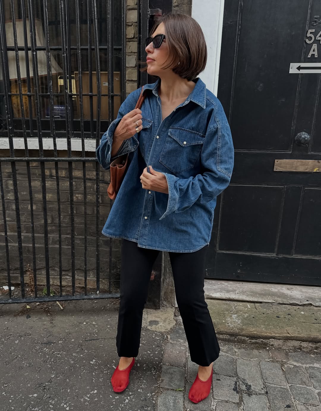 Influencer Lucy Alston wearing red shoes with black trousers.