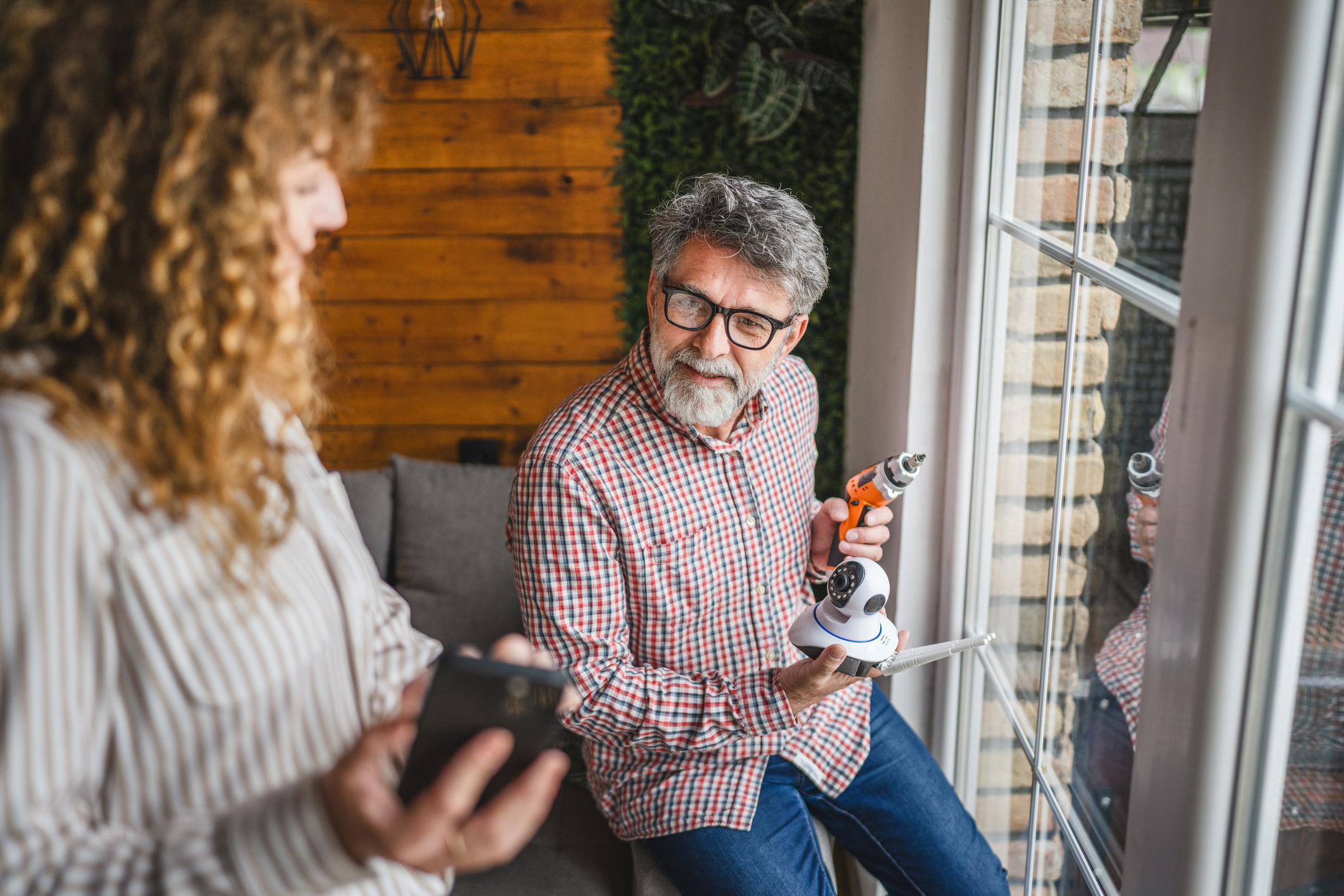 A man and woman work together to install a security camera in their home.