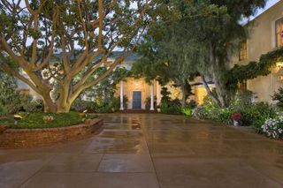 Exterior shot of the drive of a home with large trees and columns either side of the front door