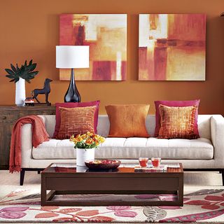 living room with orange wall and pillows on couch