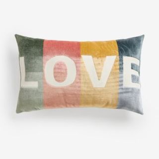 A rectangular cushion in soft pastel hues, the word LOVE embroidered across it in white