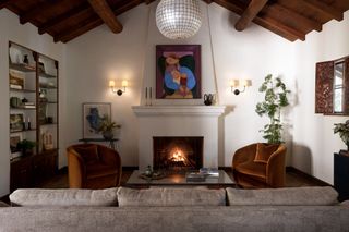 A living room with a vaulted ceiling, a lit fireplace, and two dark orange accent chairs