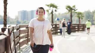 Women walking on a beachfront listening to music and holding a water bottle