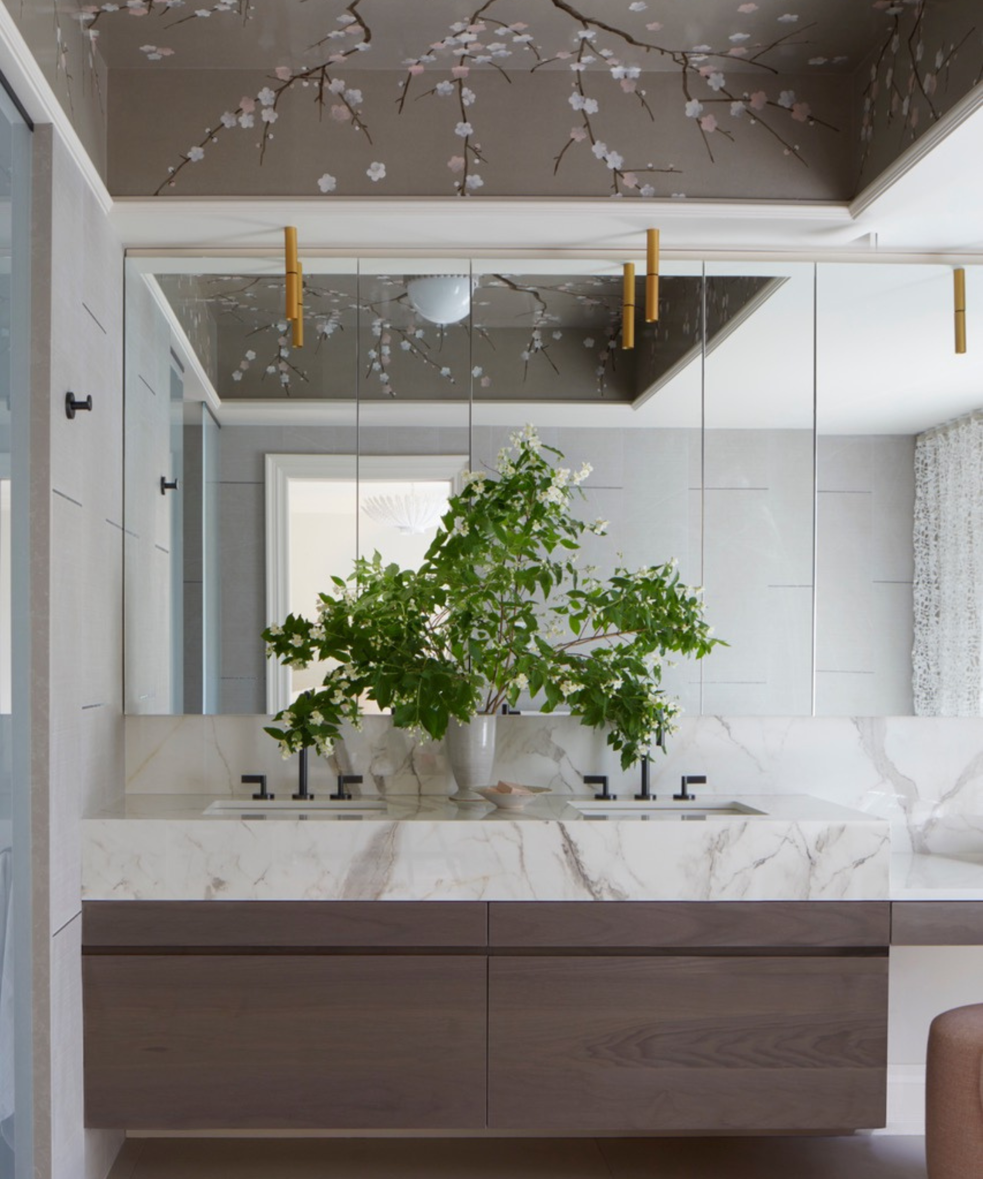a modern bathroom with dark wood cabinetry, a marble countertop, a plant on the counter, and a cherry blossom painted ceiling